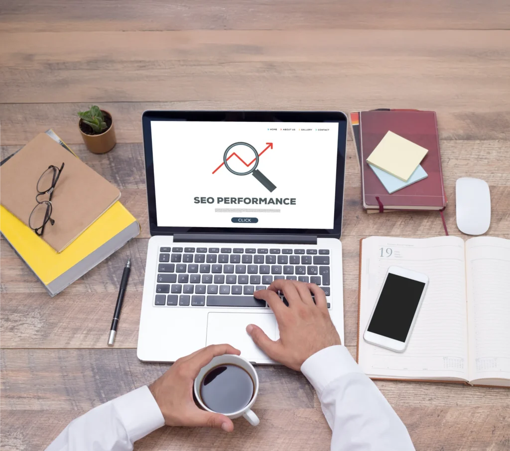 Birou cu laptop pe care scrie SEO performance, jurnal și cafea, imagine pentru audit și analiză SEO gratuită